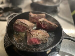 QUNIOMI主廚使用鐵鍋慢煎熊本赤牛赤身和牛，焦香四溢，展現職人技藝